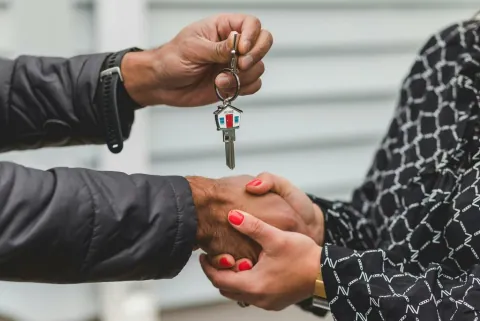 A hand holding a silver house key